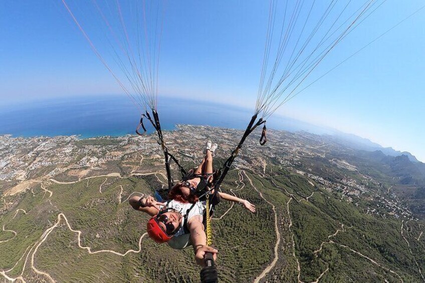 A person paragliding over a mountainous landscape with a clear view of the coastline below. 4