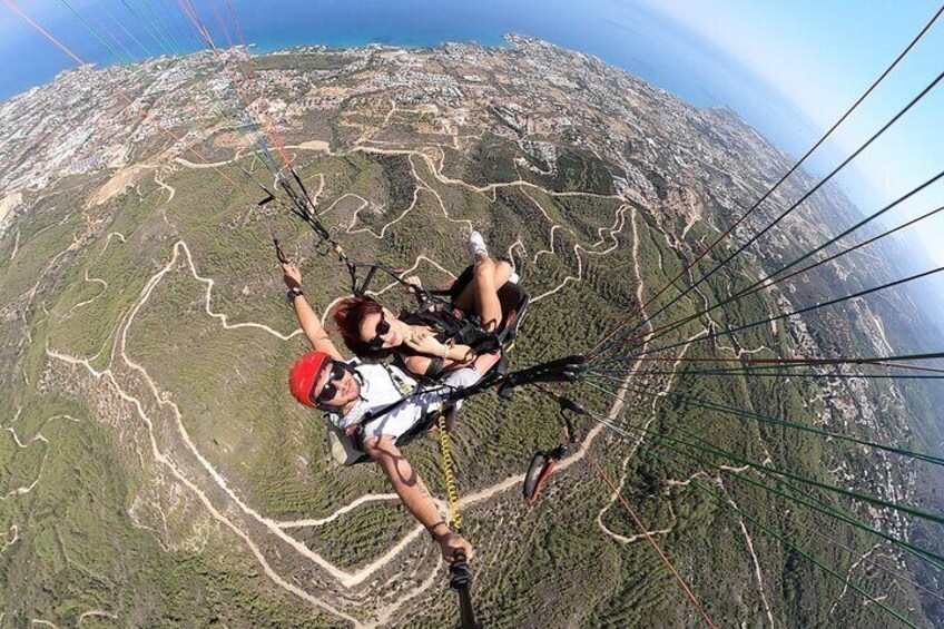 A person paragliding over a mountainous landscape with visible trails and a clear sky. 2