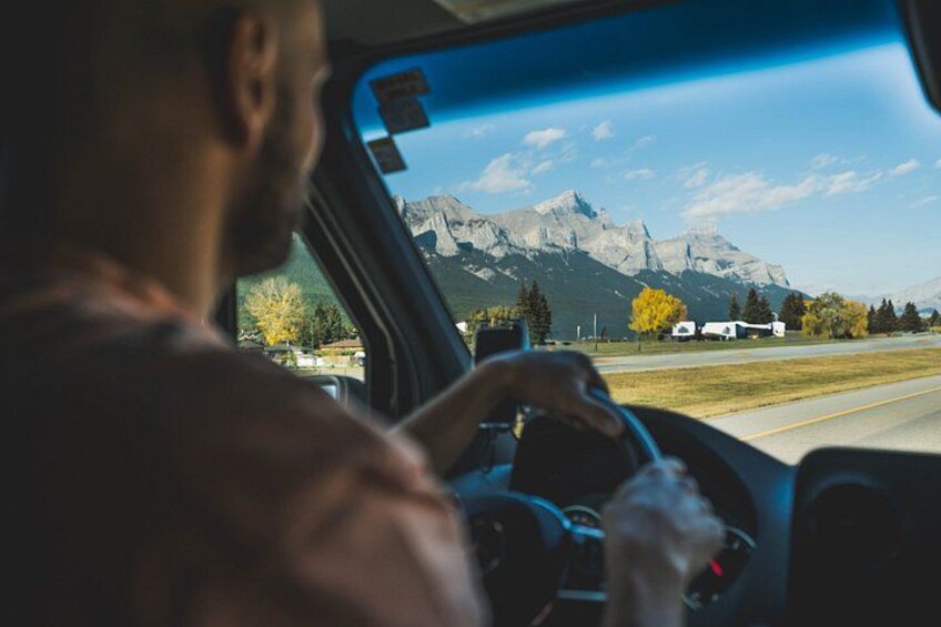 A person driving a car with a mountainous landscape in the background. 4