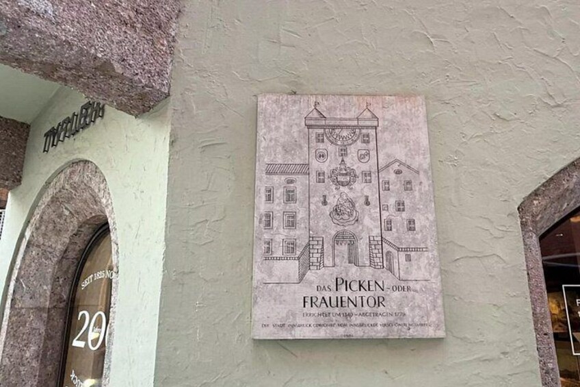 A building facade with a sign that reads 'Das Picken - Frauentor' and a door labeled '20'. 4