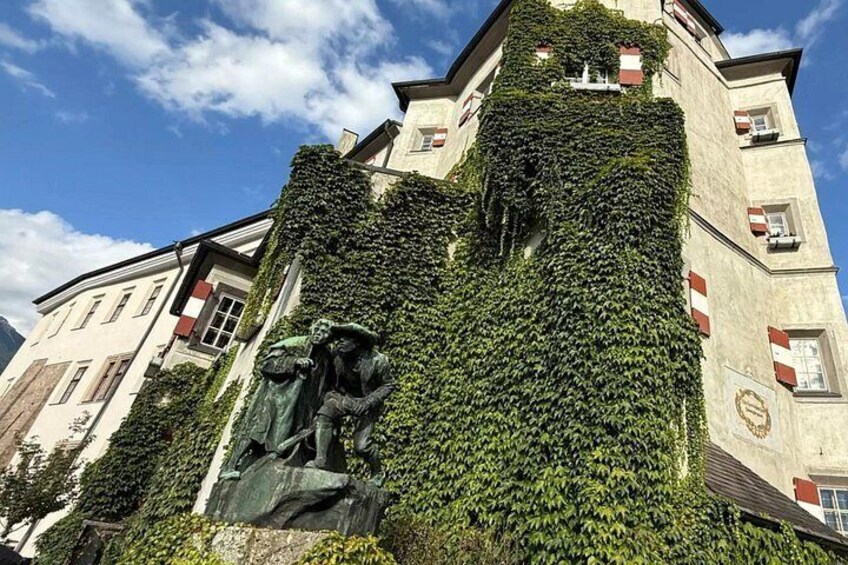 A building covered in ivy with a statue in front. 5