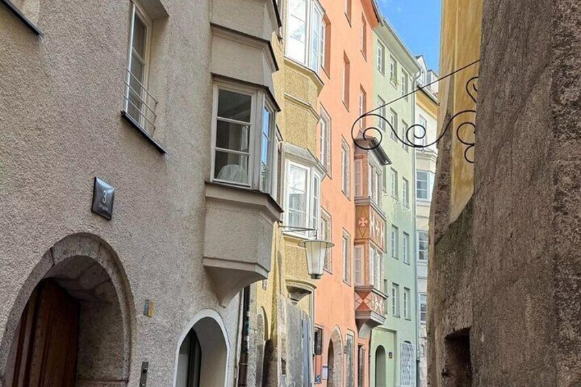 A narrow street with colorful buildings, a stone archway, and a wrought iron light fixture. 3