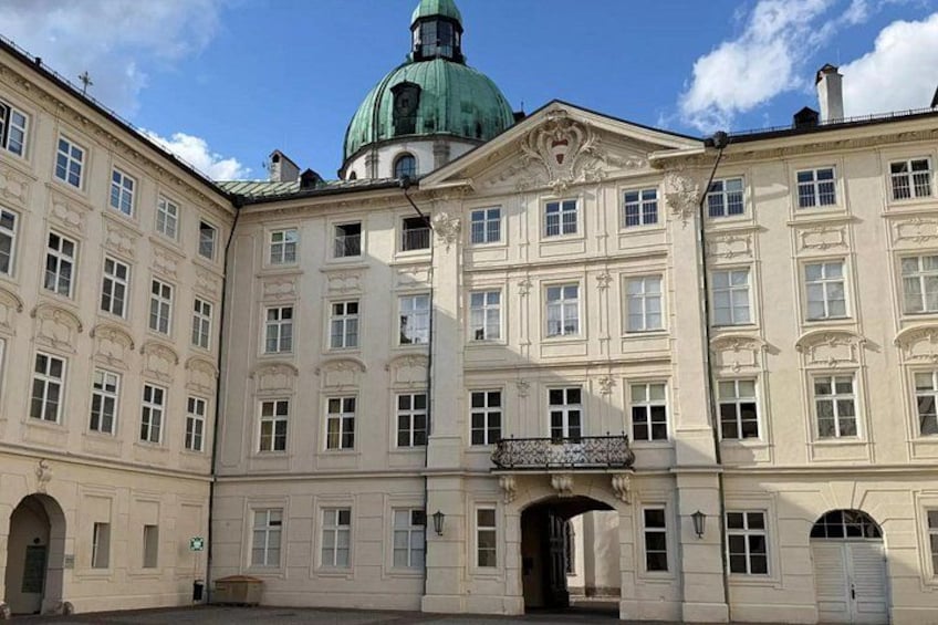 A historic building with a green dome, ornate architecture, and a central entrance. 3