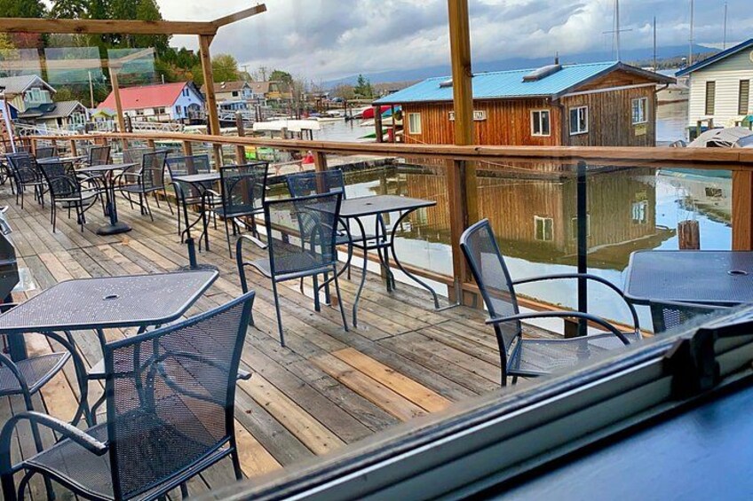 Eine Holzterrasse mit Metalltischen und -stühlen mit Blick auf eine Marina. 2
