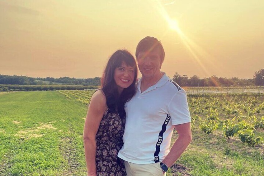 Two people standing in a field with a sunset in the background. 1