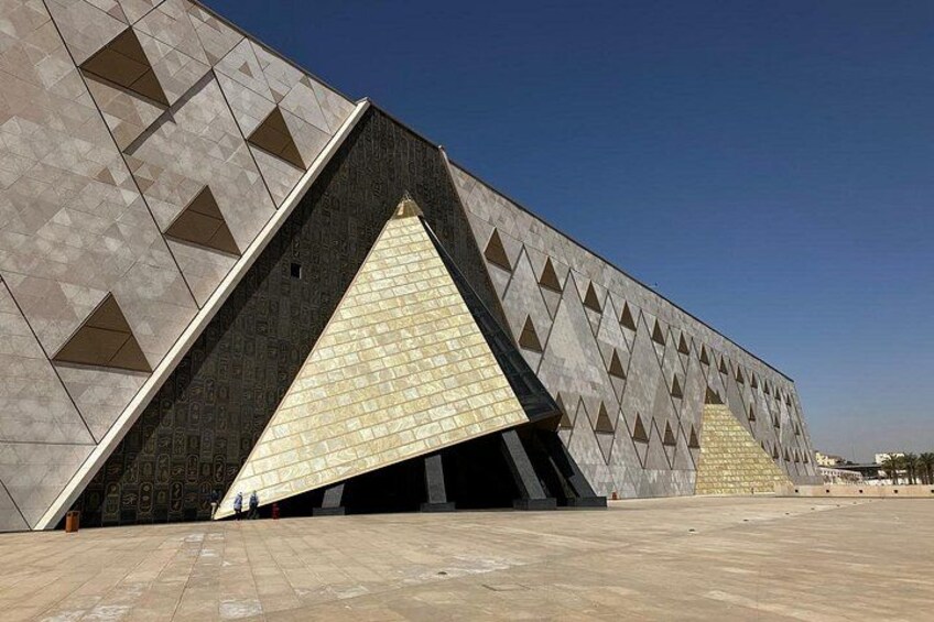 Una estructura arquitectónica moderna con un diseño geométrico, que presenta patrones triangulares y una entrada amplia. 5