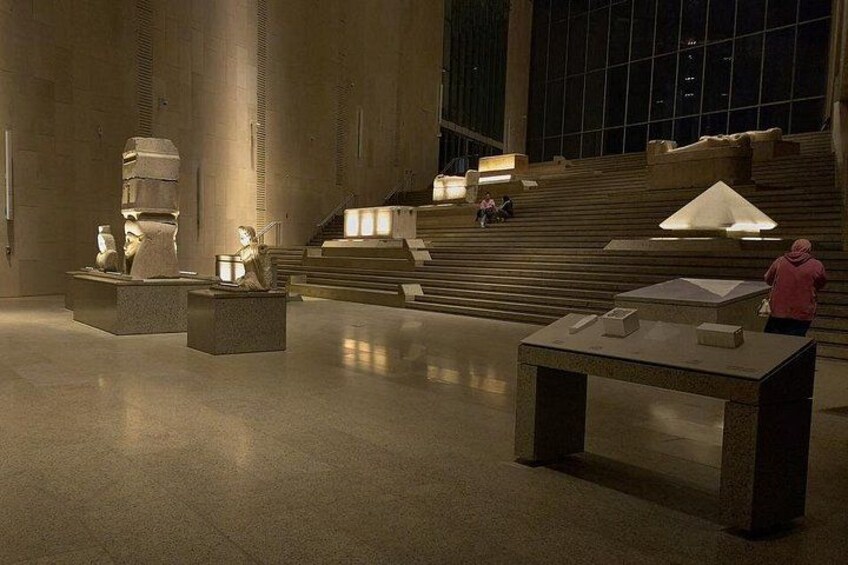 Interior de un museo con esculturas de piedra y una escalera. 3