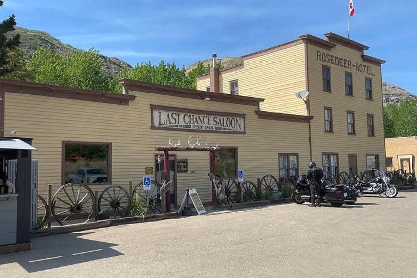 A building with a sign reading 'ROSEDEER-HOTEL' and 'LAST CHANCE SALOON.' 2