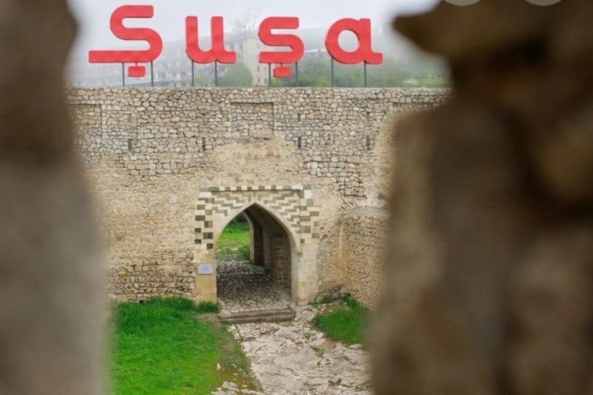 A stone bridge with an archway, a stone wall, and greenery. 1