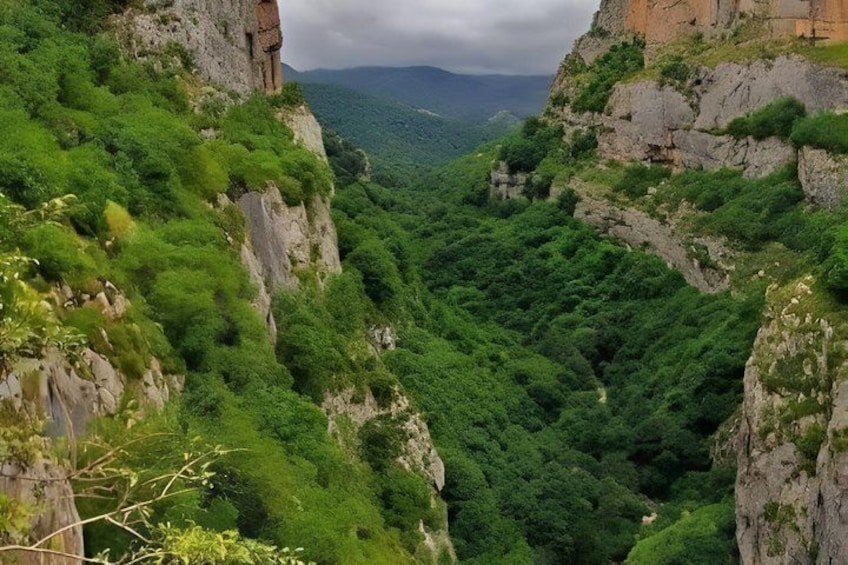 A canyon with steep cliffs and dense green vegetation. 2
