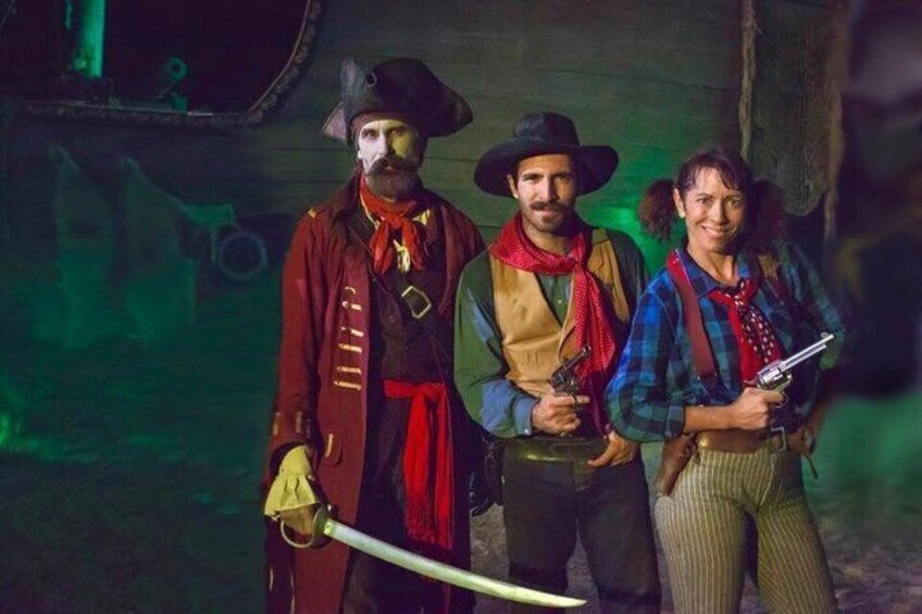 Three people in historical costumes with swords, standing in a dimly lit room. 4