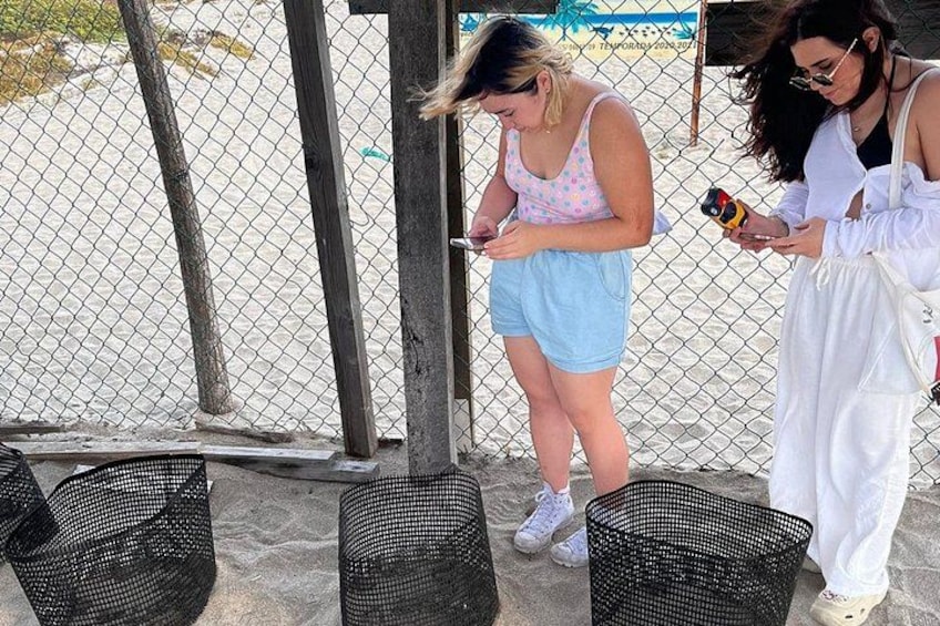 Twee personen staan bij een hek, één met een telefoon en de ander met een camera. 3
