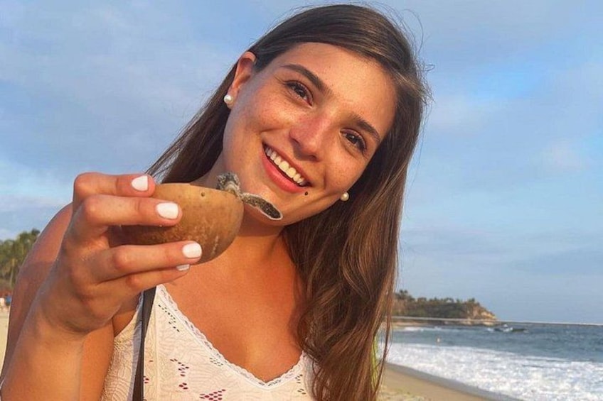 Iemand houdt een schelp vast op het strand, met golven in de verte. 1