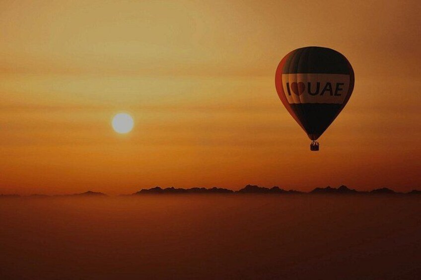 A hot air balloon with 'UAE' written on it, flying during sunset with mountains in the background. 4