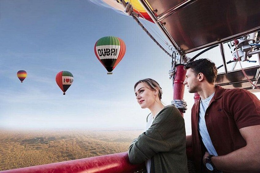 A couple on a hot air balloon with the word 'DUBAI' on one balloon. 1