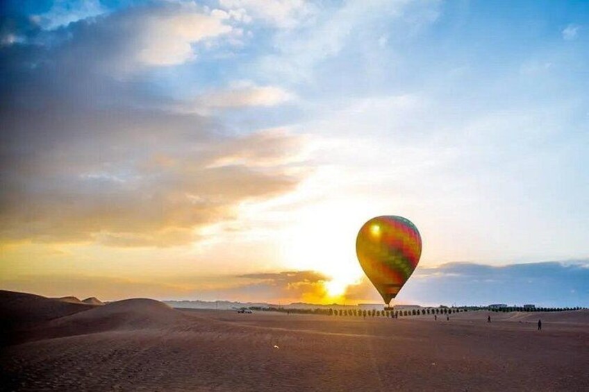 A hot air balloon over a desert landscape with a sunset in the background. 5