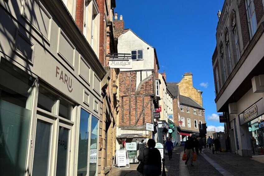 A street with shops, including one with a 'FARU' sign, and pedestrians walking. 4