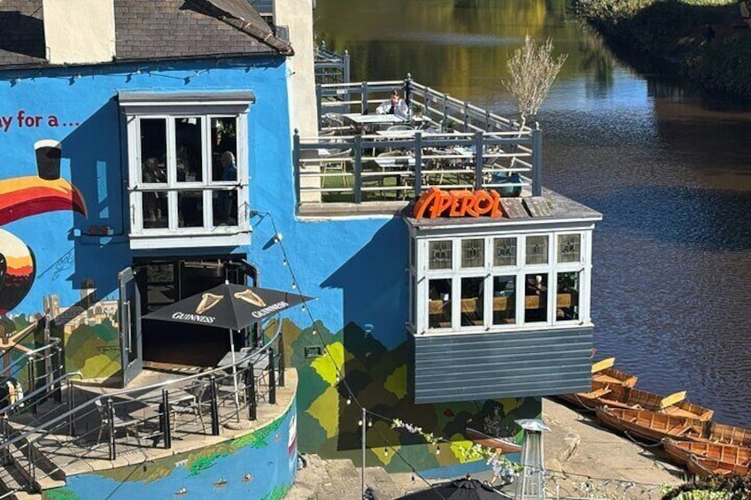 A blue building with a mural, a dock with boats, and a sign that reads "Aperox". 2