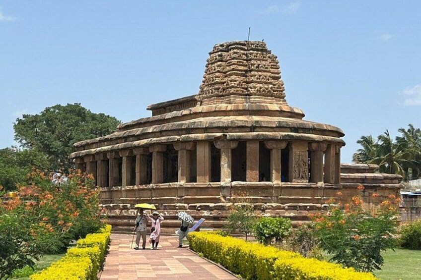 A temple with a tiered tower, surrounded by a garden with yellow flowers and green shrubs. 1