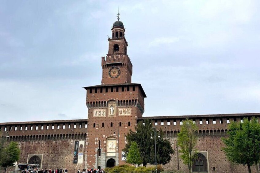 A large brick building with a clock tower, arched windows, and a gate. 3