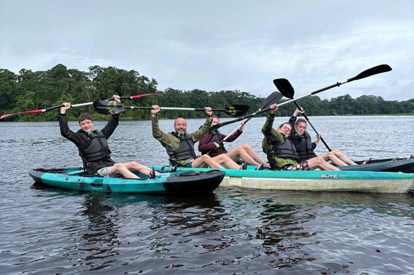 Trois personnes en kayak sur un lac paisible, avec des arbres en arrière-plan. 1