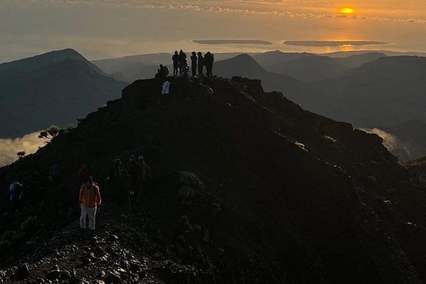 Un grupo de personas en la cima de una montaña al atardecer. 3