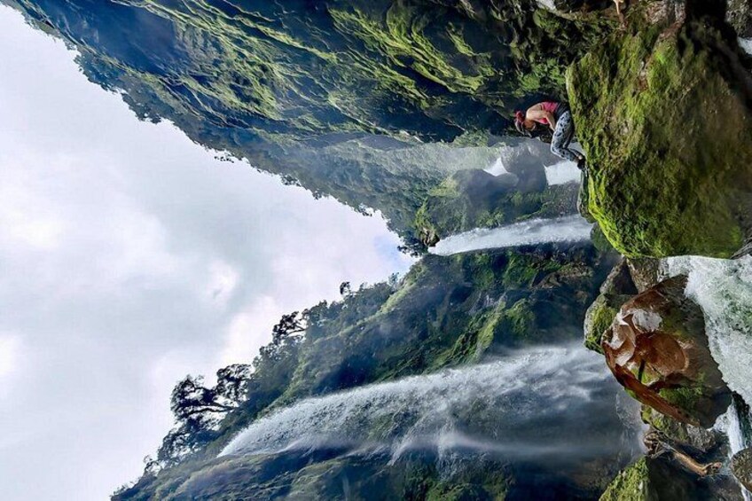 Ein Wasserfall stürzt über eine felsige Klippe, eine Person steht am Rand. 3