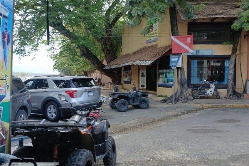 A street with parked vehicles, including a silver SUV, a quad bike, and a motorcycle. 5