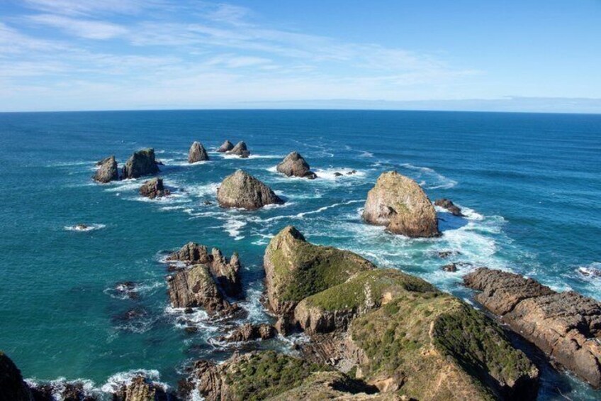 A coastal landscape with prominent rock formations and clear blue waters. 4