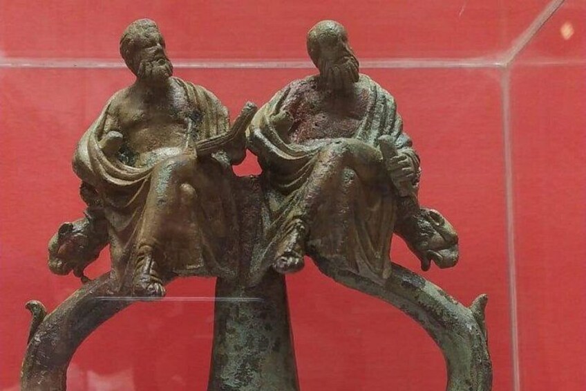 Una escultura de bronce muestra dos figuras sentadas sobre una estructura curva. 3