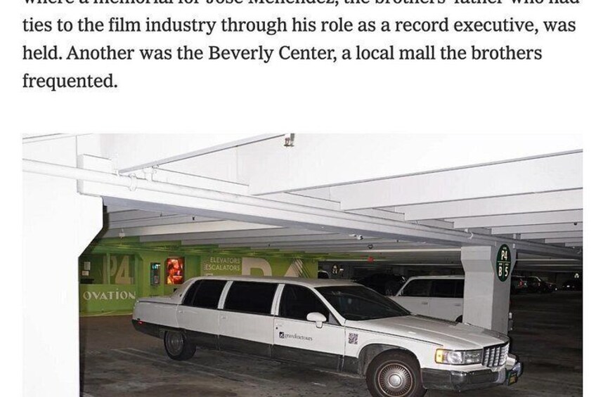 A white limousine parked in a covered parking area with a green wall and a sign that reads 'Elevator Escalators.' 3