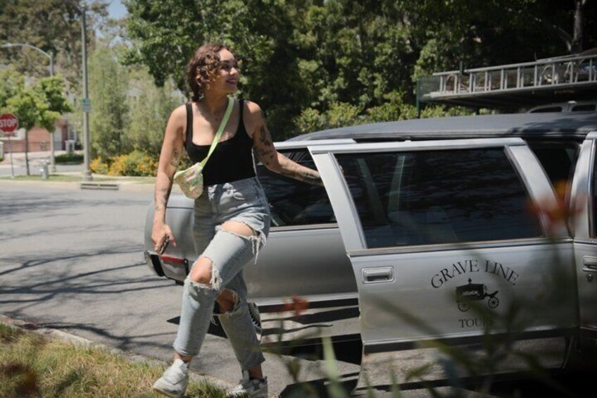 A person walking past a silver SUV with 'GRAVE LINE' and 'TOUR' written on it. 4