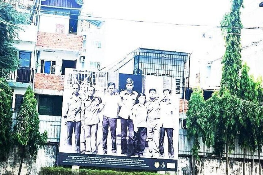 A group of people standing in front of a building with a signboard. 3