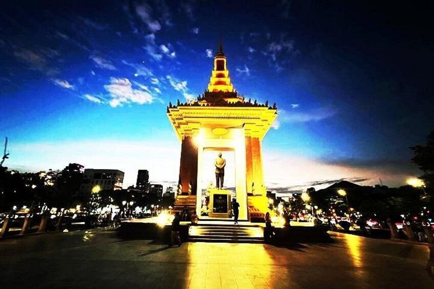 A brightly lit monument with a statue in the center, surrounded by a plaza with a crowd. 5