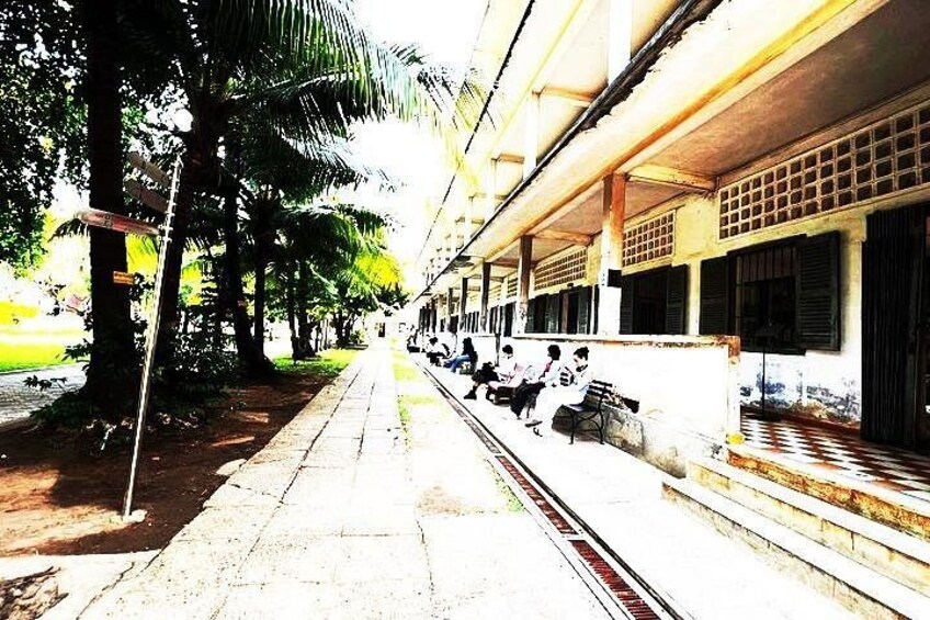 A train station platform with benches, palm trees, and a train track. 4