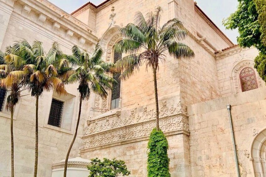 A historic building with ornate carvings and palm trees in front. 5