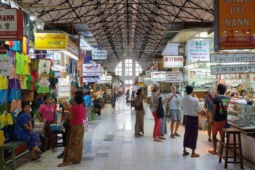 A bustling indoor market with various stalls selling goods, including jewelry and clothing. 1