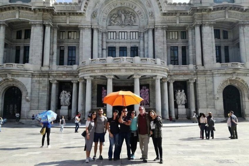 A group of people standing in front of a large, classical building with columns and statues. 1