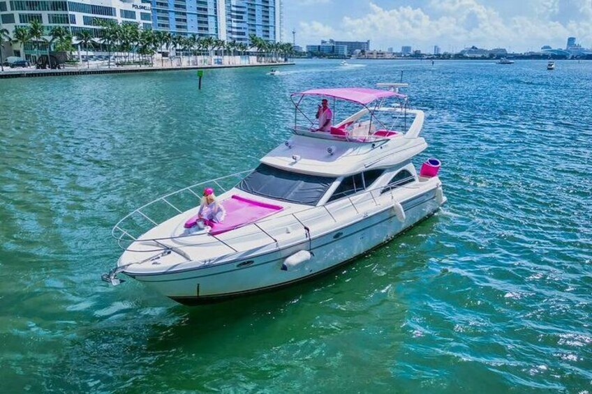 A white yacht with pink accents on a calm body of water. 2