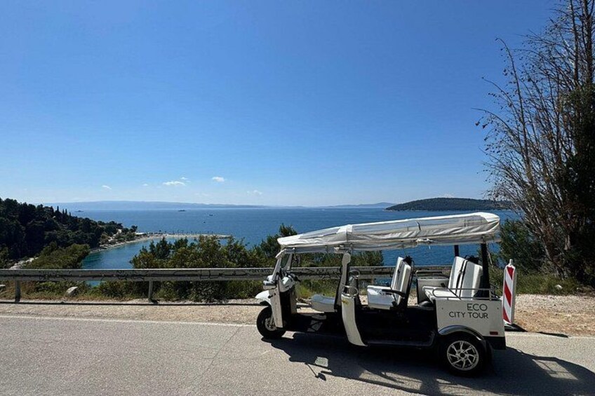 Un golf cart parcheggiato su una strada con vista panoramica su un lago e montagne sullo sfondo. 5