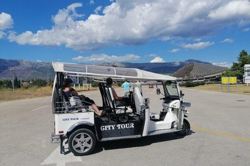 Un veicolo per tour della città parcheggiato su una strada, con montagne sullo sfondo. 2