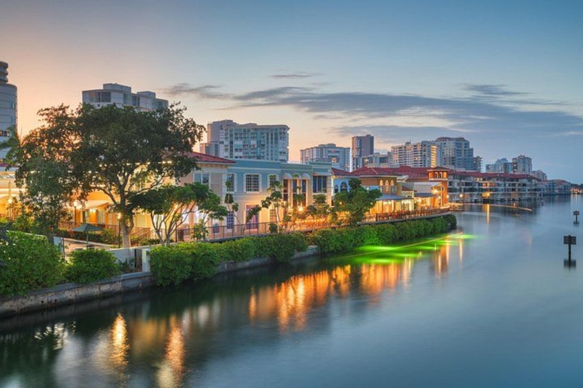 Un paisaje urbano frente al río, con edificios, agua tranquila y un cielo al atardecer. 5