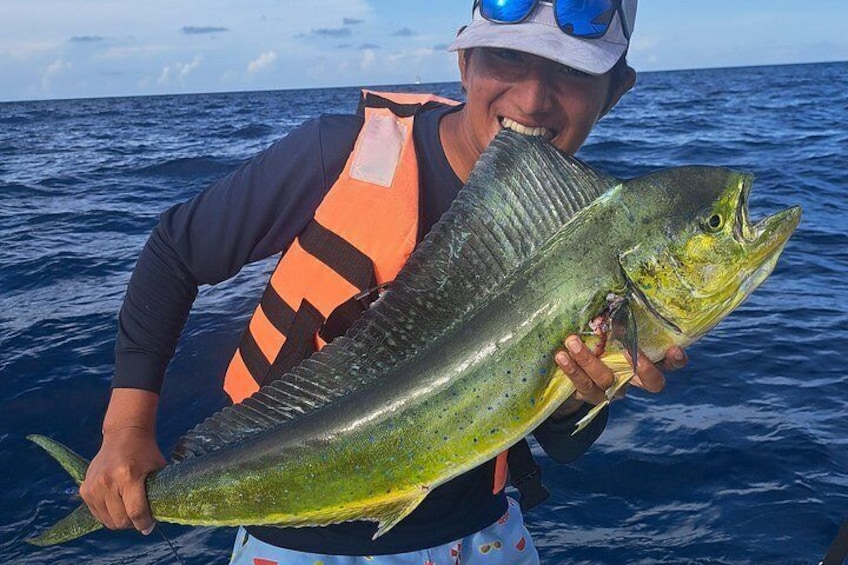 En person som håller i en stor fisk i havet. 1