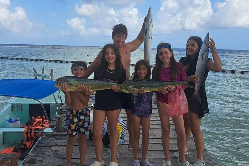 Un grupo de personas en un muelle sosteniendo peces grandes. 1