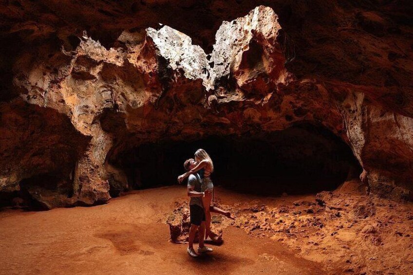 Una persona de pie en una cueva con una gran formación rocosa sobre ella. 5
