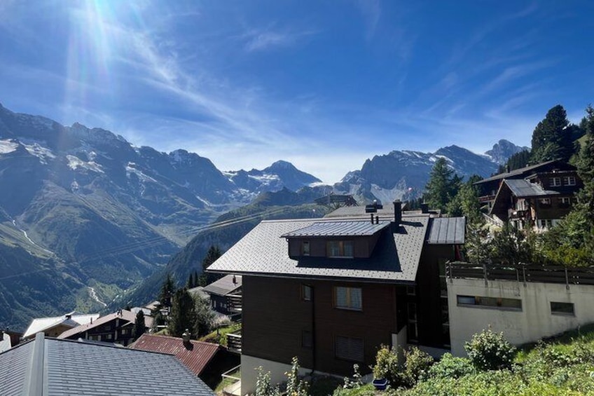 Ein Bergdorf mit Häusern, einem klaren Himmel und schneebedeckten Gipfeln im Hintergrund. 3