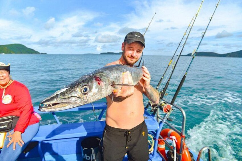 A person holding a large fish on a boat with fishing rods. 5