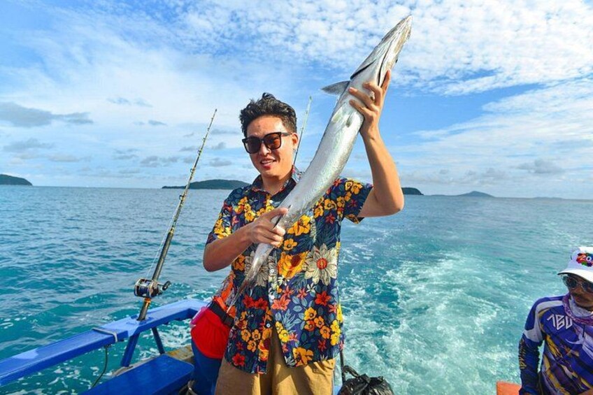 A person holding a large fish on a boat with a clear blue sky and calm sea. 2