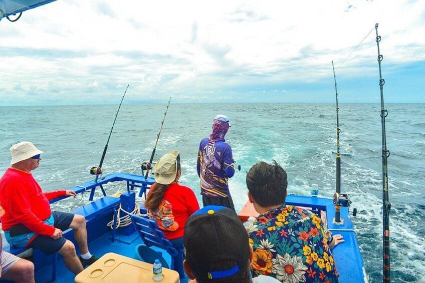 A group of people on a boat fishing in the ocean. 2