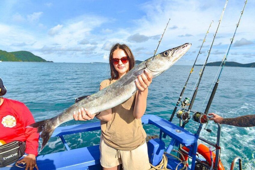 Two people on a boat holding a large fish, with fishing rods and a calm sea in the background. 4